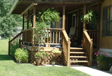 A cozy, shady porch with plenty of greenery around it.